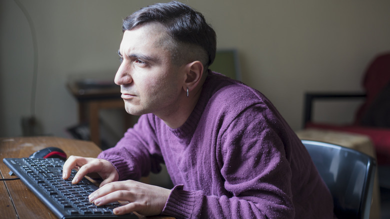 Person hunched over desk typing