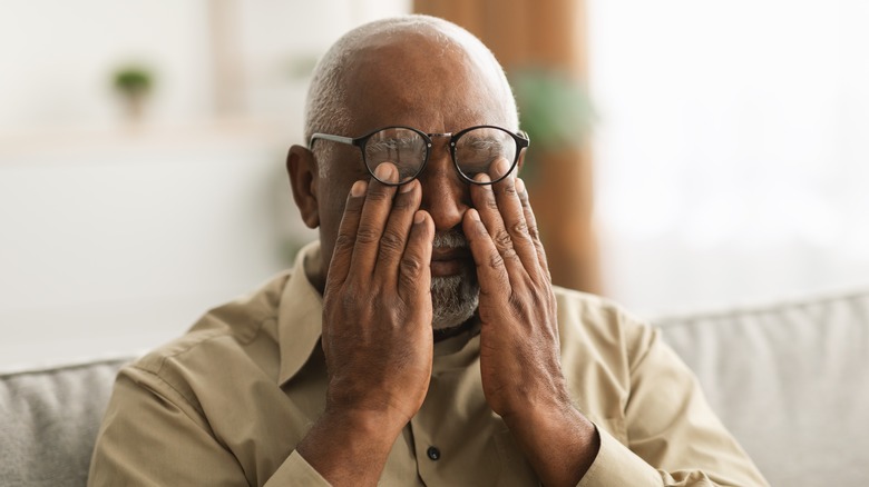 A man rubs his eyes