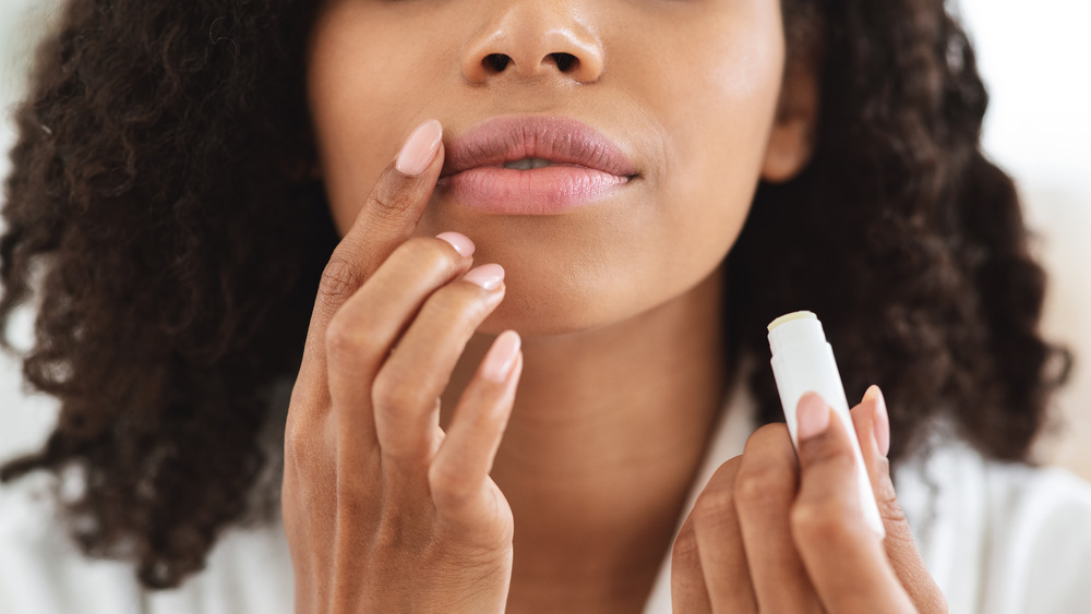 A woman applying lip balm