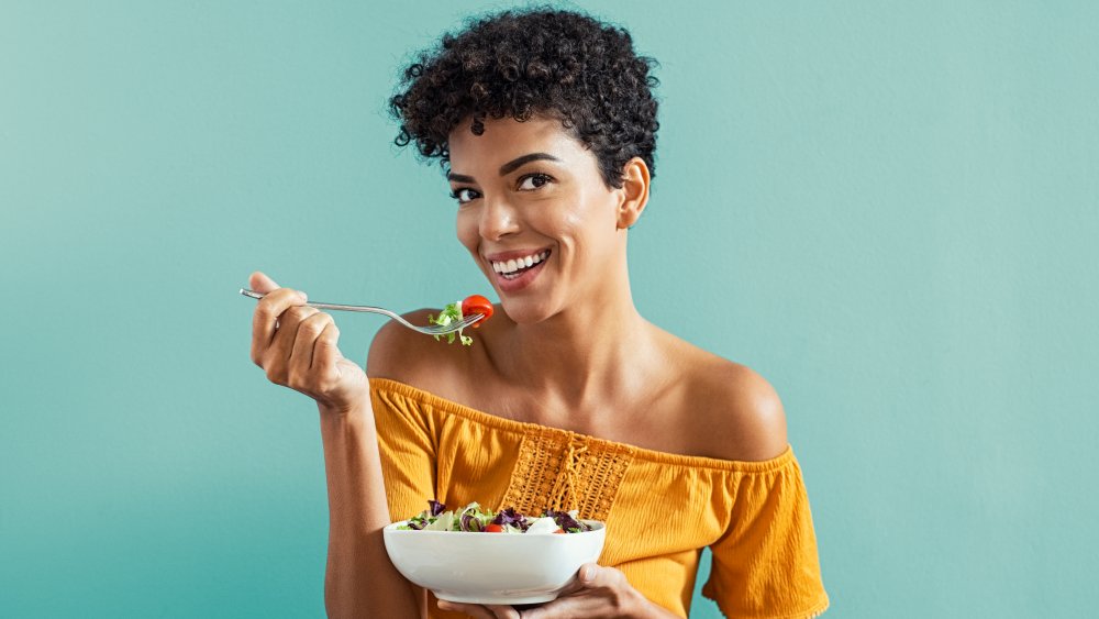 A smiling woman eating a salad