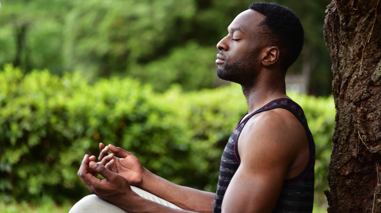 young man in park meditating