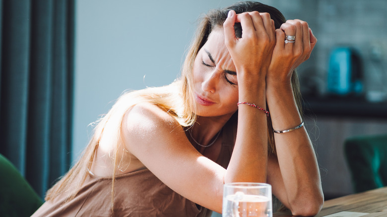 A woman sitting at a desk with her head in her hands