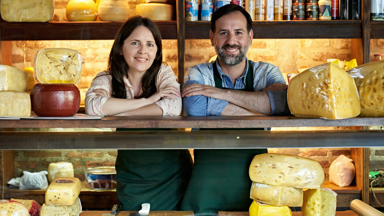 cheese store owners in front of an array of cheese