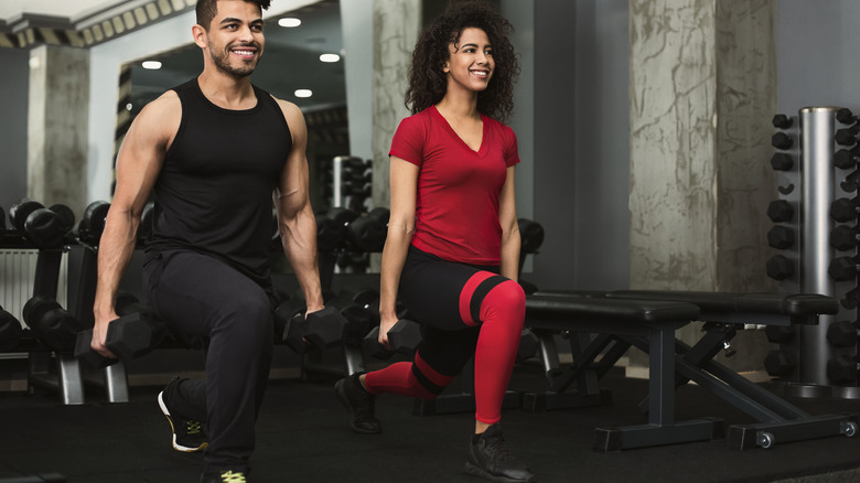man and woman lunging with weights