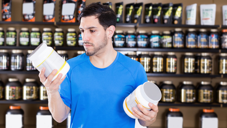 A man comparing two tubs of whey protein powder