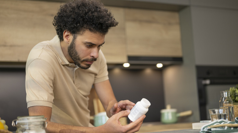 Man reading drug label on bottle