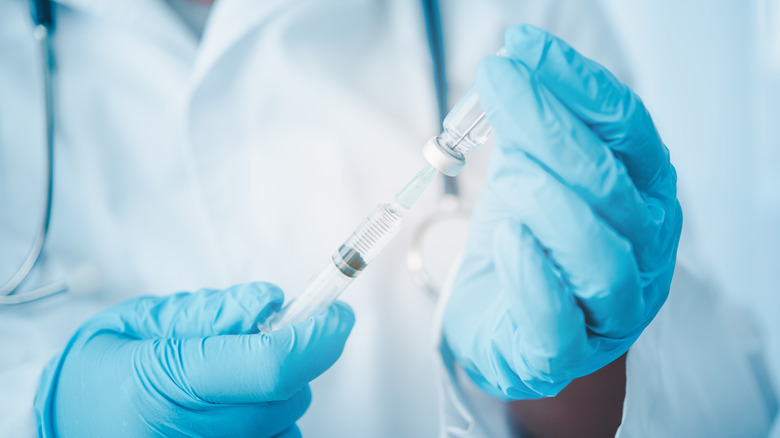gloved hands holding syringe