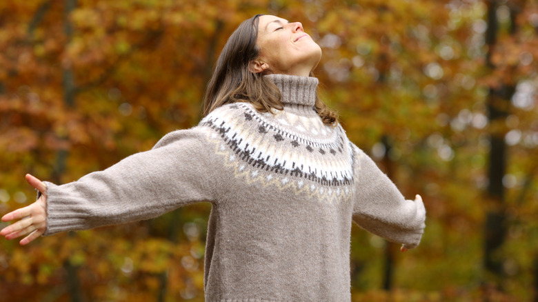 woman with outstretched arms and autumn leaves