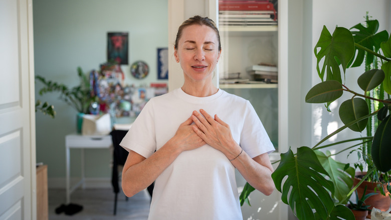 A woman with her hands over her chest, feeling her heartbeat
