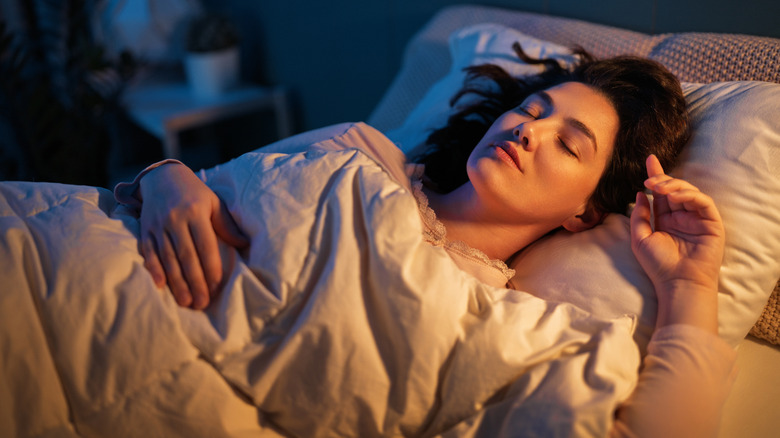 A woman asleep in her bed and dreaming
