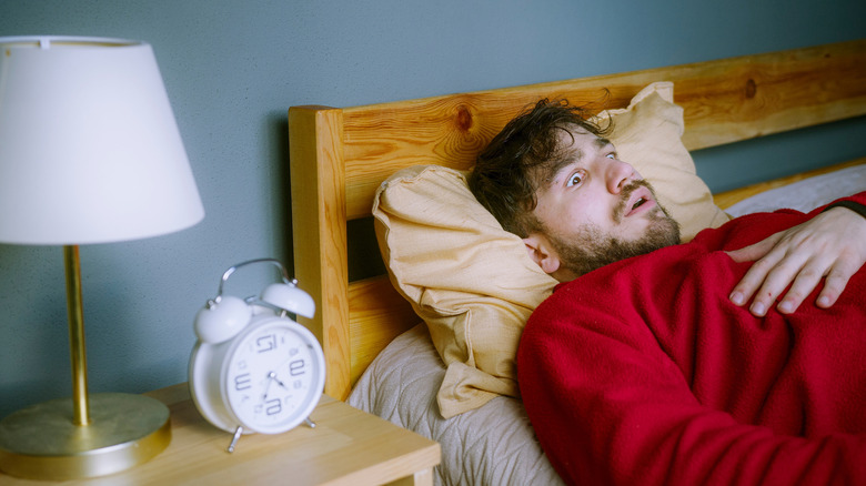 A man lying in bed frightened and unable to move