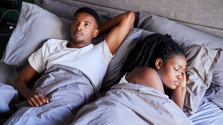 Man awake next to woman