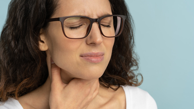 frowning woman clutching throat