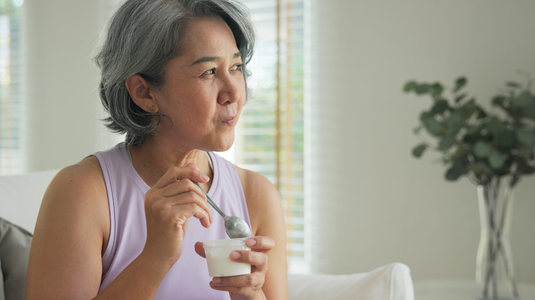 mature woman eating yogurt at home