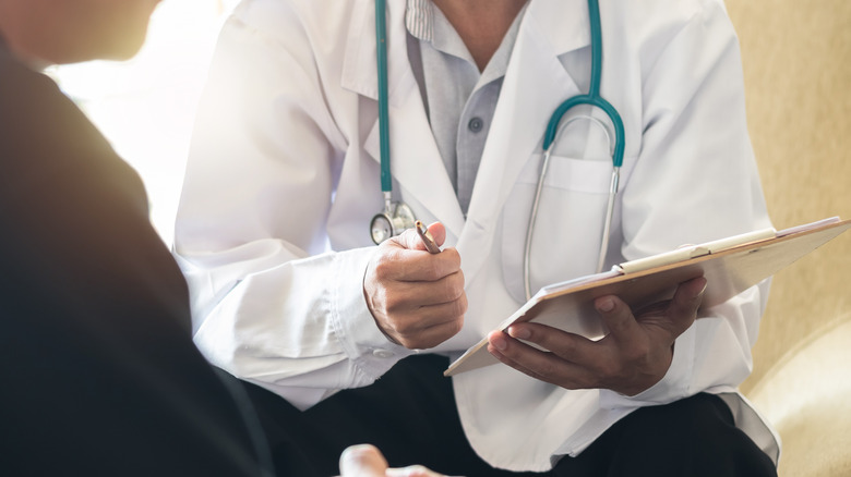 Doctor holding clipboard talking to patient