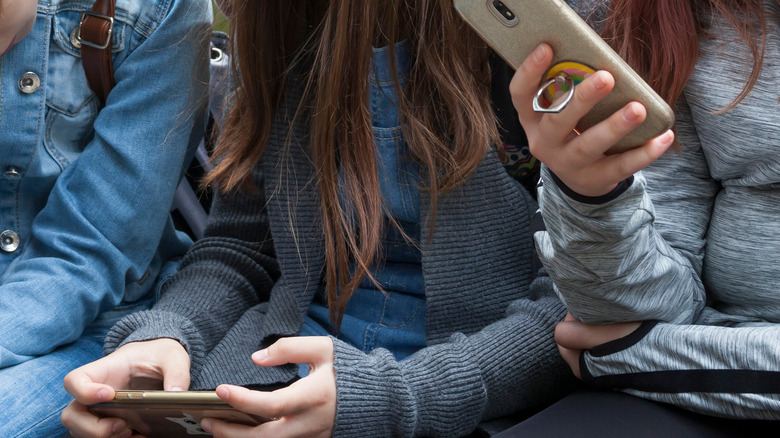 Preteen girls sitting with phones in hands