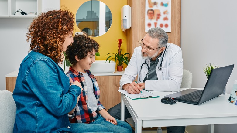 Pediatrician talks with young patient and their parent