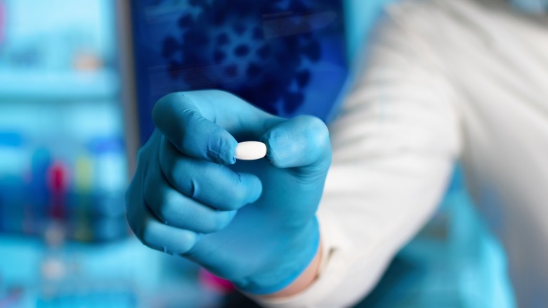 researcher holding antiviral pill in lab