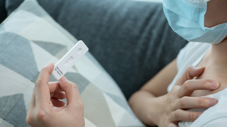 Masked person holding antigen test