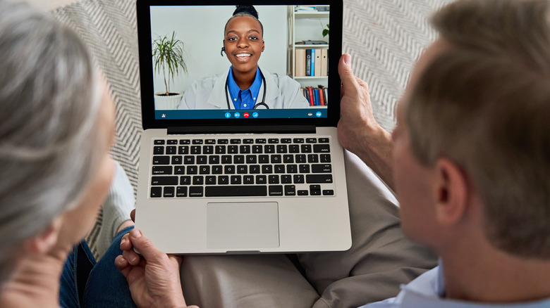Overhead view of couple participating in telehealth appointment on a laptop 