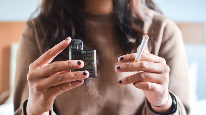 woman holding cigarette and vape