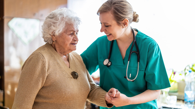 Nurse helping walk an elderly patient across the room