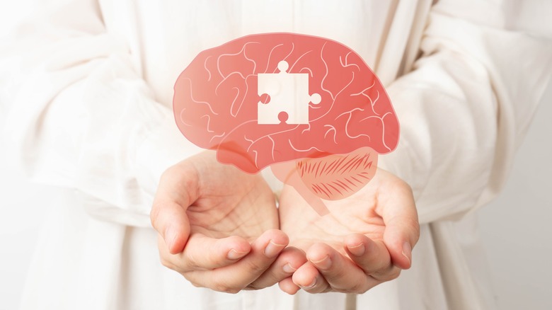 Doctor hands holding an image of a brain with a missing puzzle piece