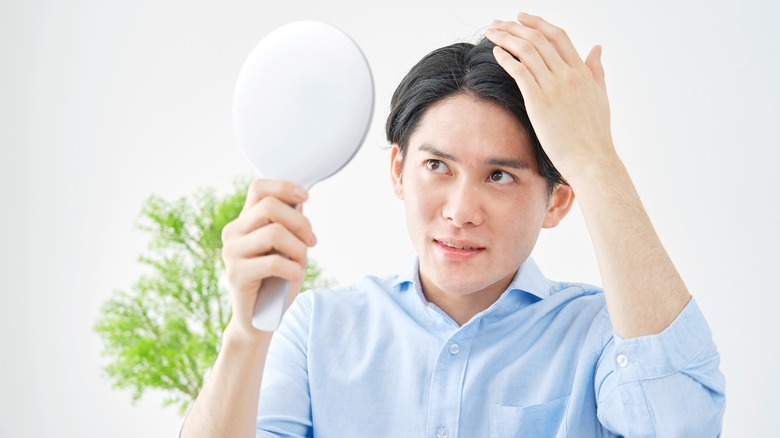 Young man checking hair in mirror
