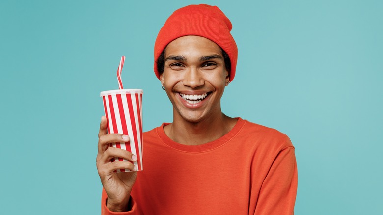 Smiling young man holding soda