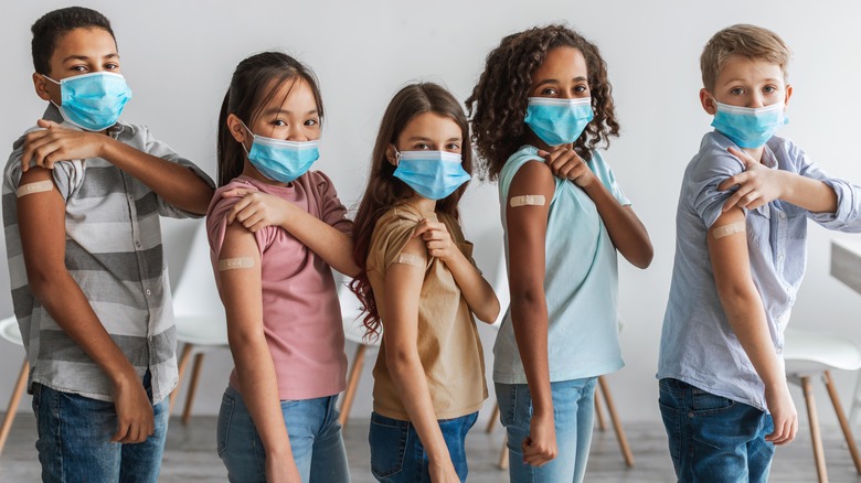 diverse group of children with masks showing their band-aids