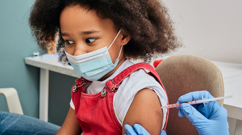 African American girl with mask on getting a shot