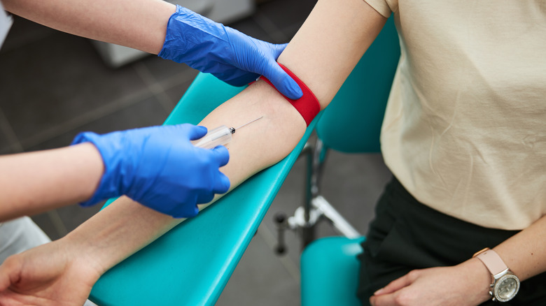 female getting blood drawn from arm by phlebotomist