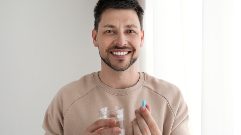 smiling man holding pill
