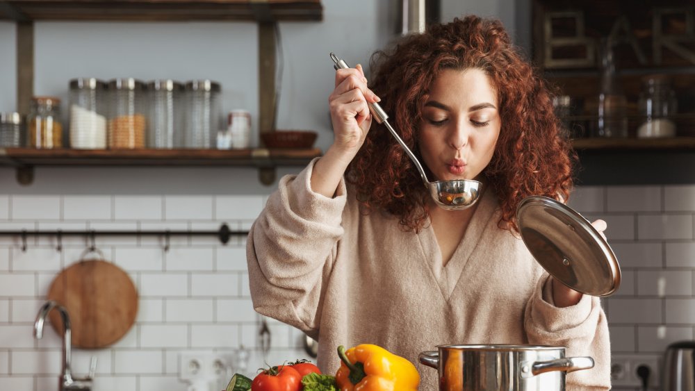 woman tasting food from a spoon in the kitchen