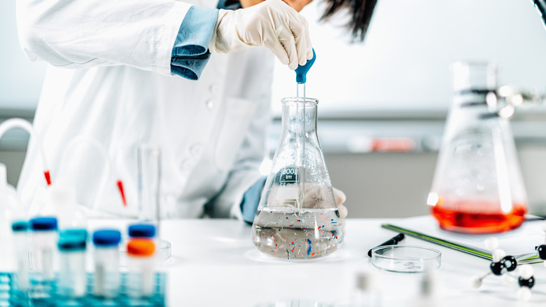 scientist with microplastics in a beaker