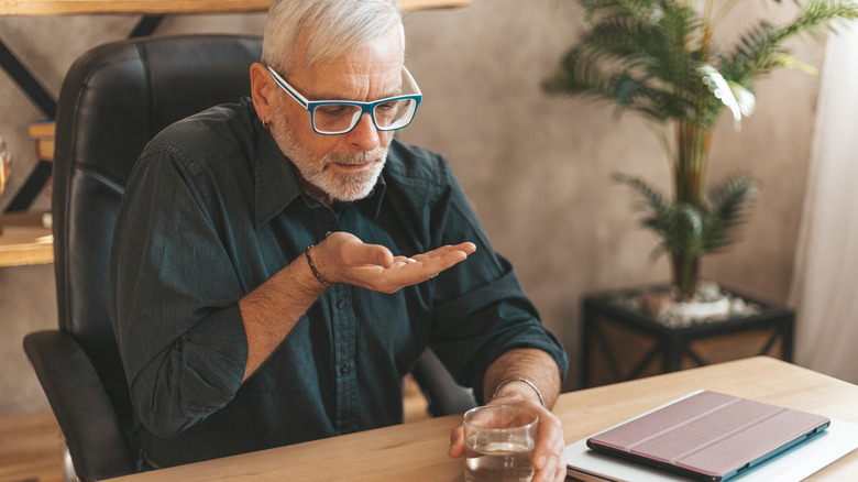 older man taking vitamin