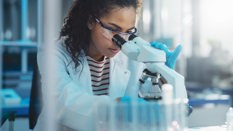 Female research scientists looks through microscope