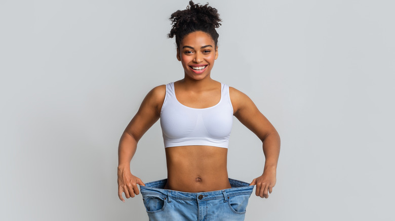 woman smiling while wearing old jeans after losing weight