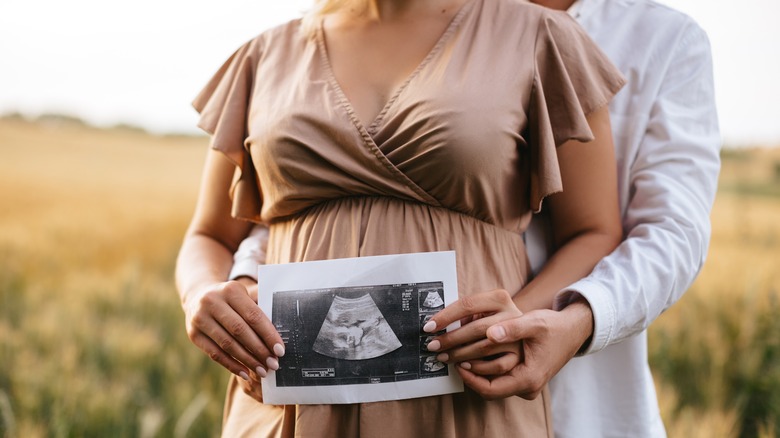 faceless couple holding a sonogram of baby