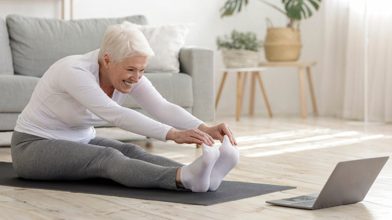 older woman doing yoga online