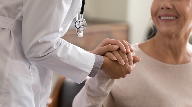 A doctor holds the hand of a patient