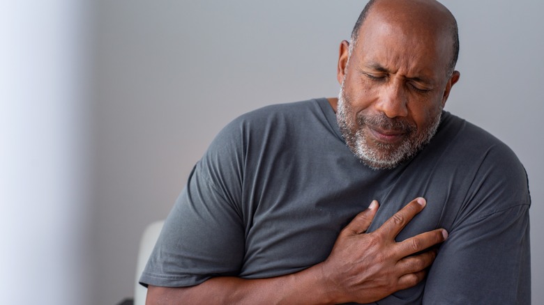 older black man hold chest in pain