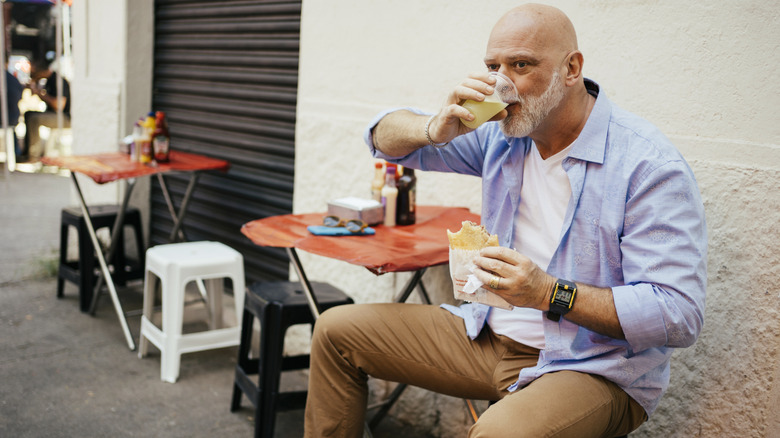 mature man drinking sugarcane juice at street table