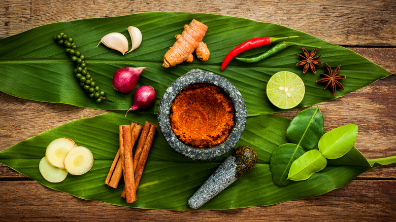 Assorted herbs on leaves with mortar and pestle