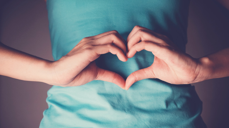 A woman makes a heart with her hands over her stomach