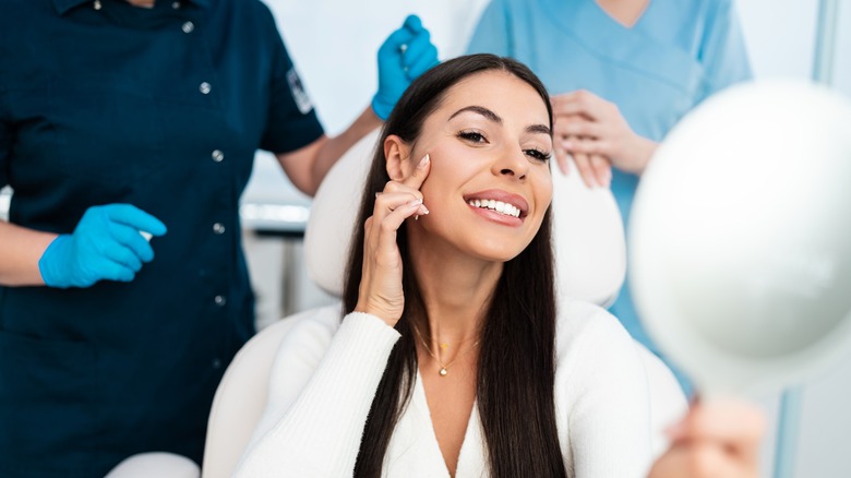 Woman looks in mirror after cosmetic procedure