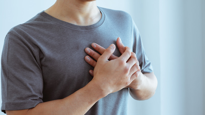 Man in gray tee with hands on chest