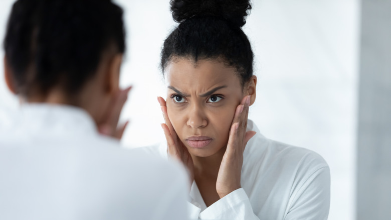 woman unhappy skin mirror