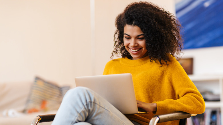 young woman smiling as she views laptop