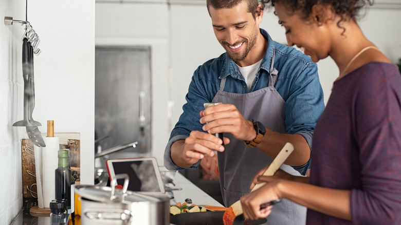 man and woman cooking with pepper